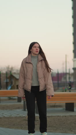 een jong meisje in een perzikjas en zwarte broek rolt langs een parkweg. de opname, genomen van voren, vangt haar gefocuste uitdrukking terwijl ze geniet van de activiteit