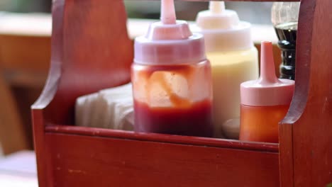 persona colocando una botella de salsa en una canasta de madera.