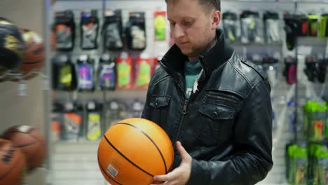 Ein-Erwachsener-Mann-In-Schwarzer-Lederjacke-Wählt-In-Einem-Sportgeschäft-Einen-Basketballball-Aus