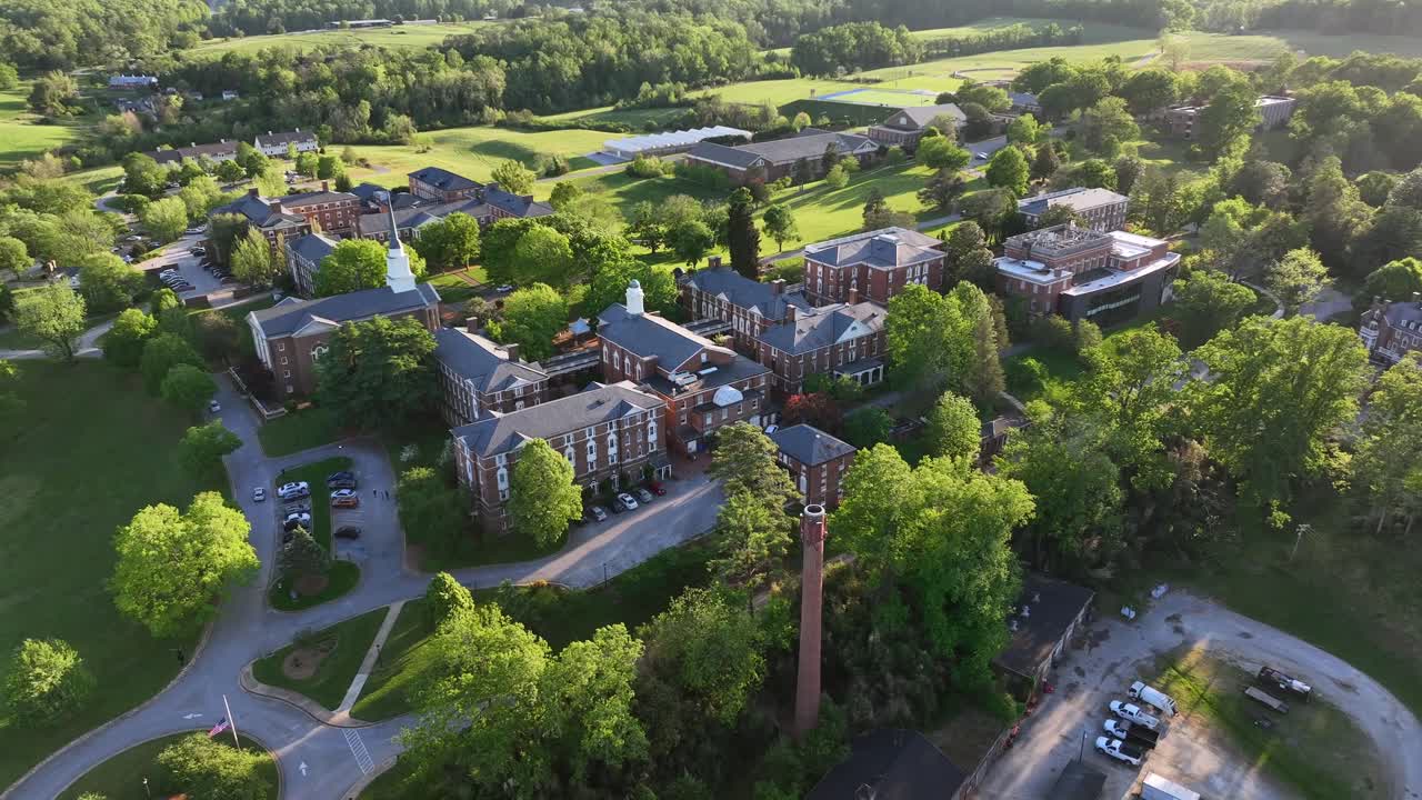 Aerial orbit shot of historic Sweet Briar College and Church tower in Lynchburg, VA. Sunset time in lush scenic landscape. Panorama wide shot.
