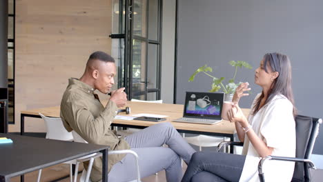 discussing work, colleagues drinking coffee and using laptop in modern office