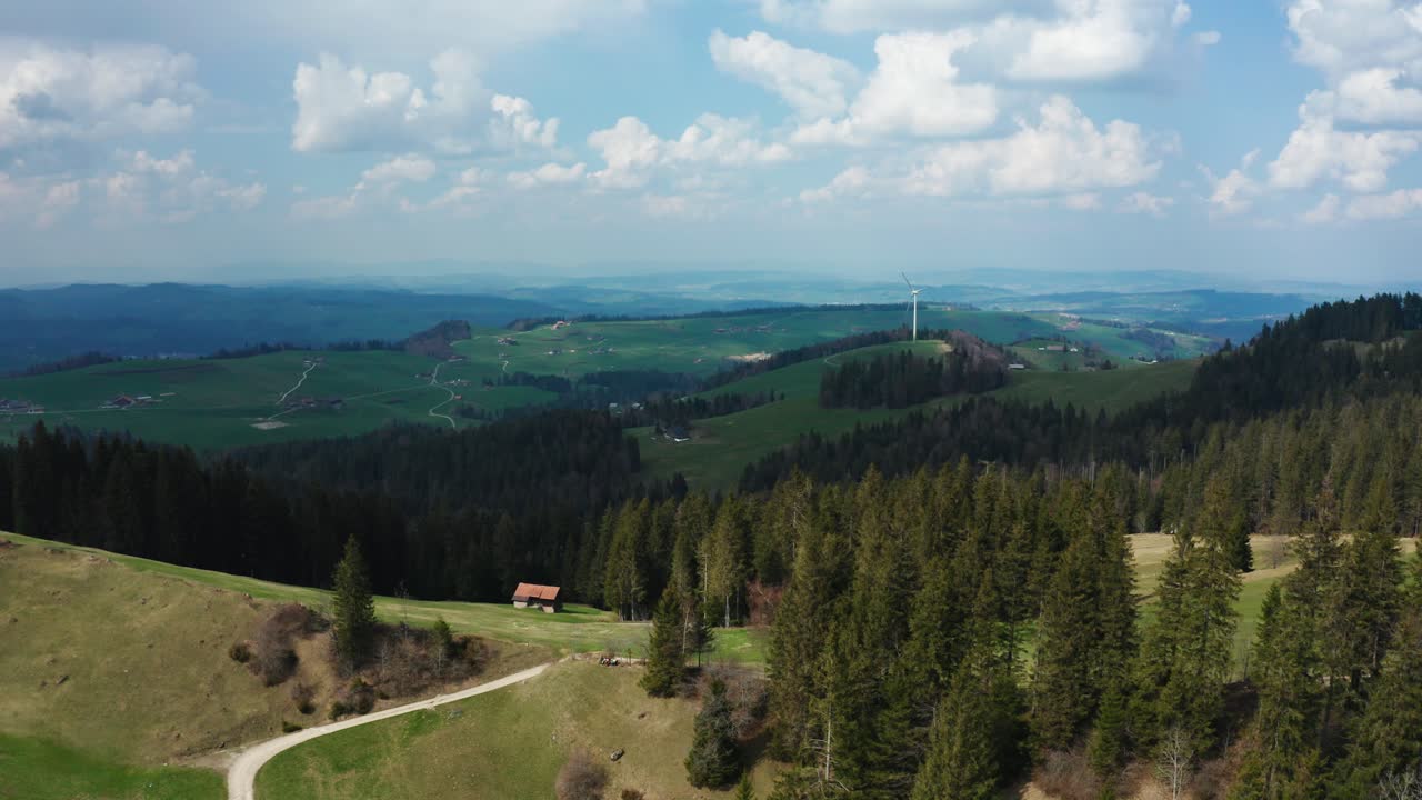 vista aérea de un solo molino de viento en el campo suizo con pinos, energía renovable de turbinas de energía eólica