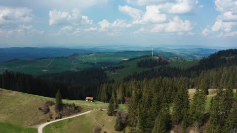 Vista-Aérea-De-Un-Solo-Molino-De-Viento-En-El-Campo-Suizo-Con-Pinos,-Energía-Renovable-De-Turbinas-De-Energía-Eólica