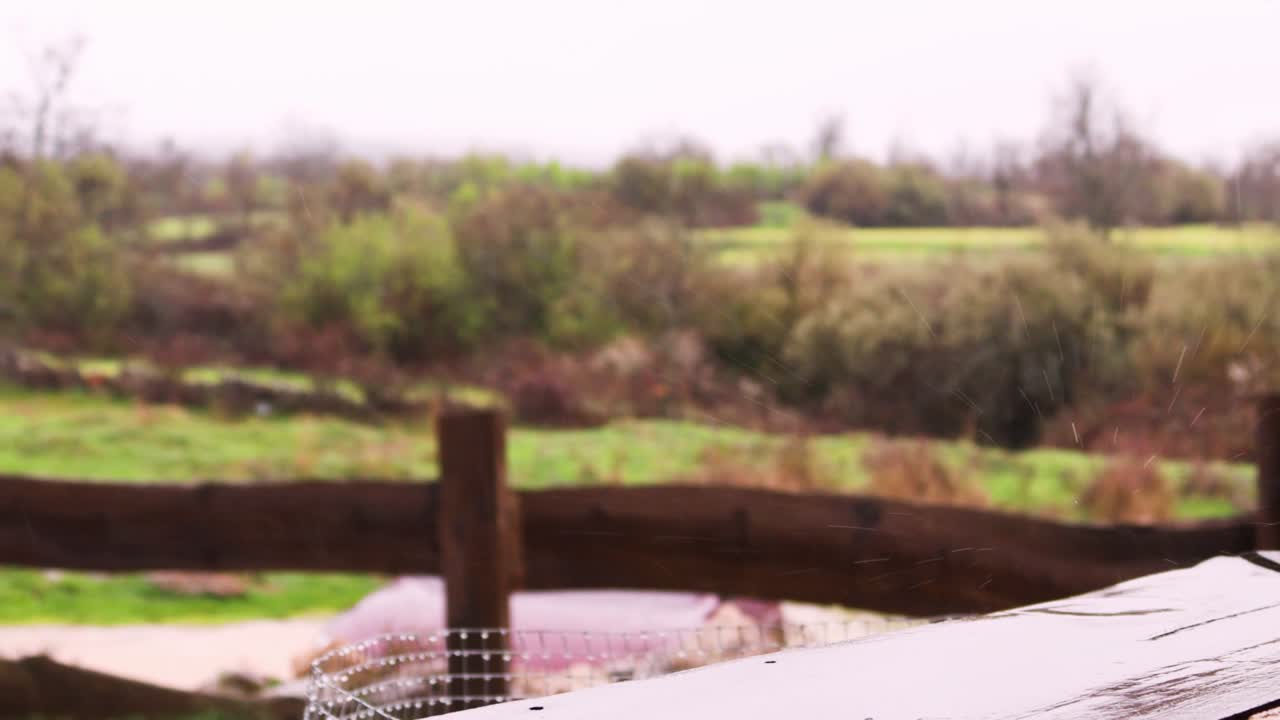 slowed down raindrops on wooden railing in the forest