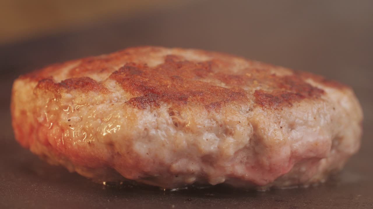 Cooking American fat smash burger on grill close-up. Beef or pork cutlet smashing by burger press. The chef in kitchen of the restaurant making cutlets for burgers - smash burger beefsteak. Fast and street food concept. High quality 4k footage