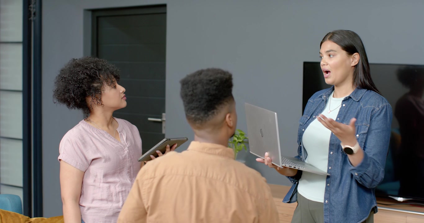 African American women and teenage son listening as right woman explaining laptop alert, tablet