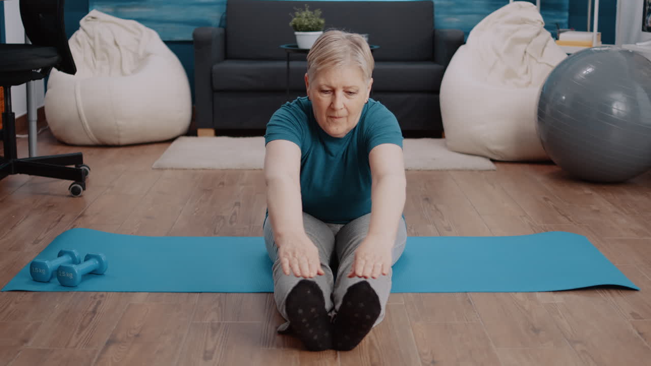 Senior woman stretching in aerobics position on yoga mat