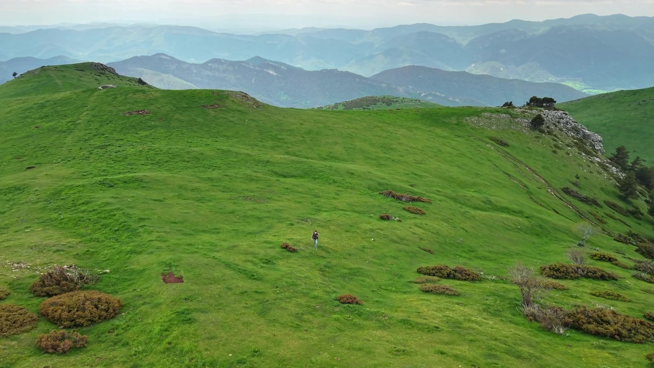Escursionista che attraversa un prato verde di montagna nei Pirenei Catalani
