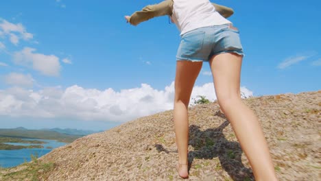 slowmo low angle, girl leaps up oceanfront dune on a beautiful cloudy day at santha martha