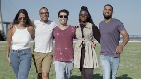 de jeunes amis heureux avec des sourires en dents marchant sur un pré vert