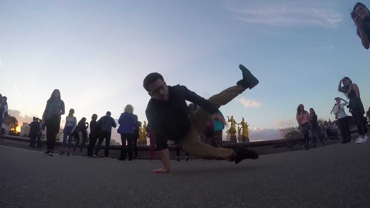 Young Caucasian man break dancing on cement ground by spectators, Moscow, Russia
