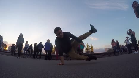 young caucasian man break dancing on cement ground by spectators, moscow, russia