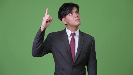 young handsome asian businessman pointing finger up