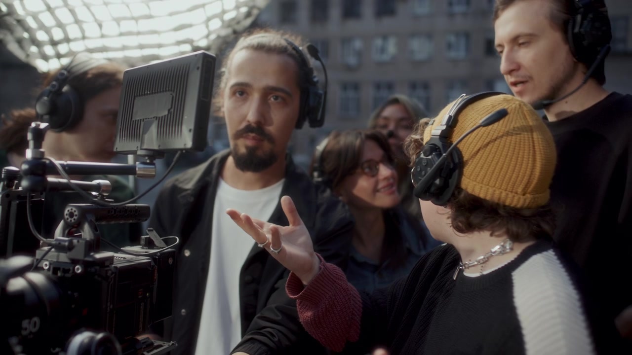Film Crew and Director Monitoring Scene on Camera Screen on Outdoor Set