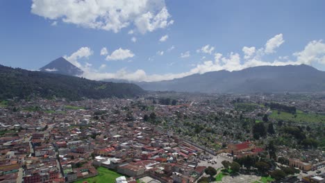 drone aerial footage of quetzaltenango xela, guatemala. zone 1 and famous cementerio general. bright partly cloudy day. city surrounded by forest hills and mountains and volcan de cerro quemado peak.