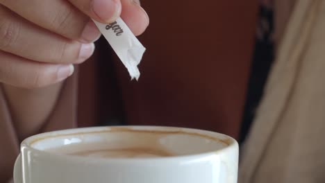 mujer añadiendo azúcar a su taza de café