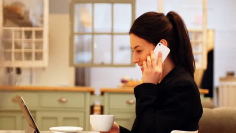mujer hablando por teléfono móvil mientras toma café