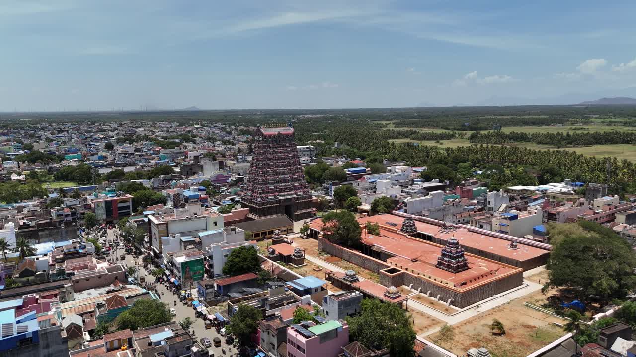 Drone footage of the historic Kasi Viswanathar Temple in Tenkasi, Tamil Nadu, featuring the temple complex, vibrant houses, and scenic green countryside under clear skies