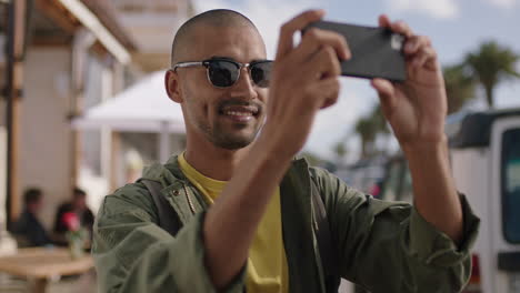 retrato de un joven atractivo con gafas de sol tomando una foto usando un teléfono