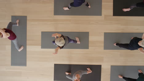 top view yoga class instructor teaching mature women practicing warrior pose enjoying healthy lifestyle in fitness studio