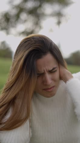 young woman experiencing headache or discomfort outdoors
