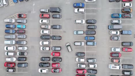 Top-down-aerial-view-of-UK-carpark-filled-with-neatly-parked-vehicles,-showcasing-different-car-models,-Devon,-UK