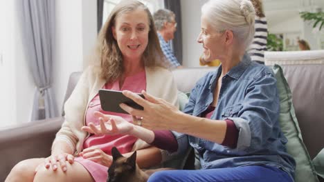 Animation-of-caucasian-female-senior-friends-using-smartphone-and-talking-on-sofa