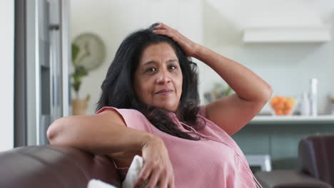 Happy-caucasian-senior-woman-sitting-on-sofa-and-smiling-in-sunny-living-room-at-home,-slow-motion