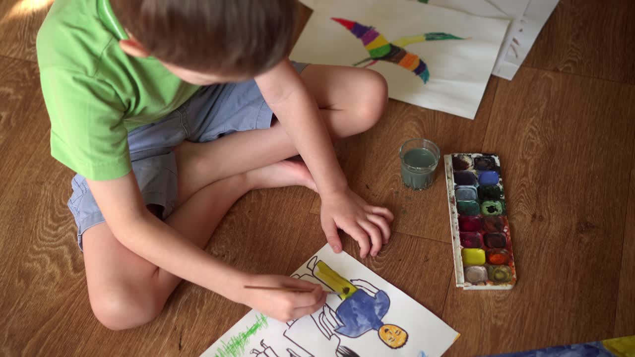 바닥에 있는 아이가 수채화로 그림을 그린다.
