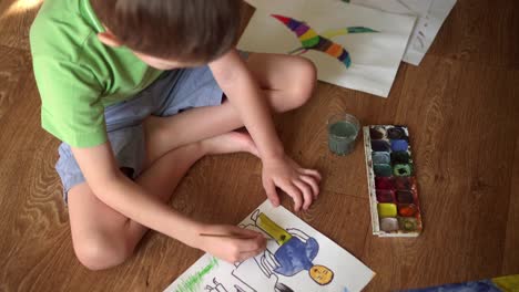 un niño en el suelo dibuja un dibujo con acuarelas 03