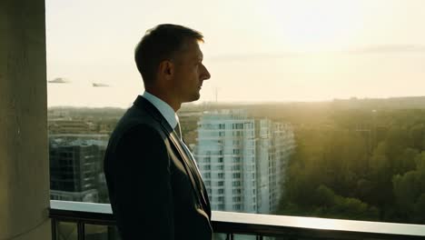 a businessman looks out at a city skyline from a rooftop.