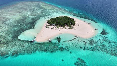 patawan island's white sand shores, lush palm canopy (cocos nucifera), and vibrant coral reef systems off the southern coast of palawan, philippines, slow drone orbit
