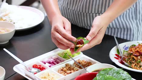 hands assembling traditional thai miang kham savoury leaf wraps carefully