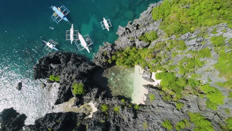 tourists swimming in hidden lagoon of the secret beach in el nido - philippines with tour boats anchored