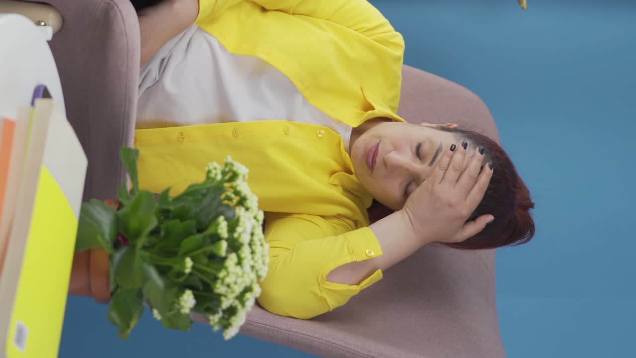 건강하지 않은 여성의 수직 비디오는 긴장을 풀기 위해 창문 밖을 바라보고 있습니다.