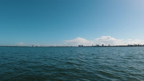 the miami skyline sandwiched between blue water and blue sky on a sunny day in miami florida from the perspective of a small boat