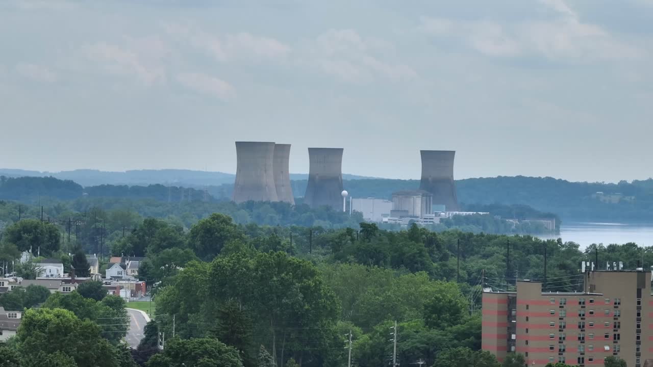 Nuclear cooling towers in suburb of American town. Aerial wide shot. Dangerous power plant producing energy. Panorama view