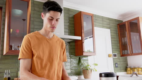 Focused-biracial-man-preparing-fruit-and-composting-waste-in-kitchen,-copy-space,-slow-motion