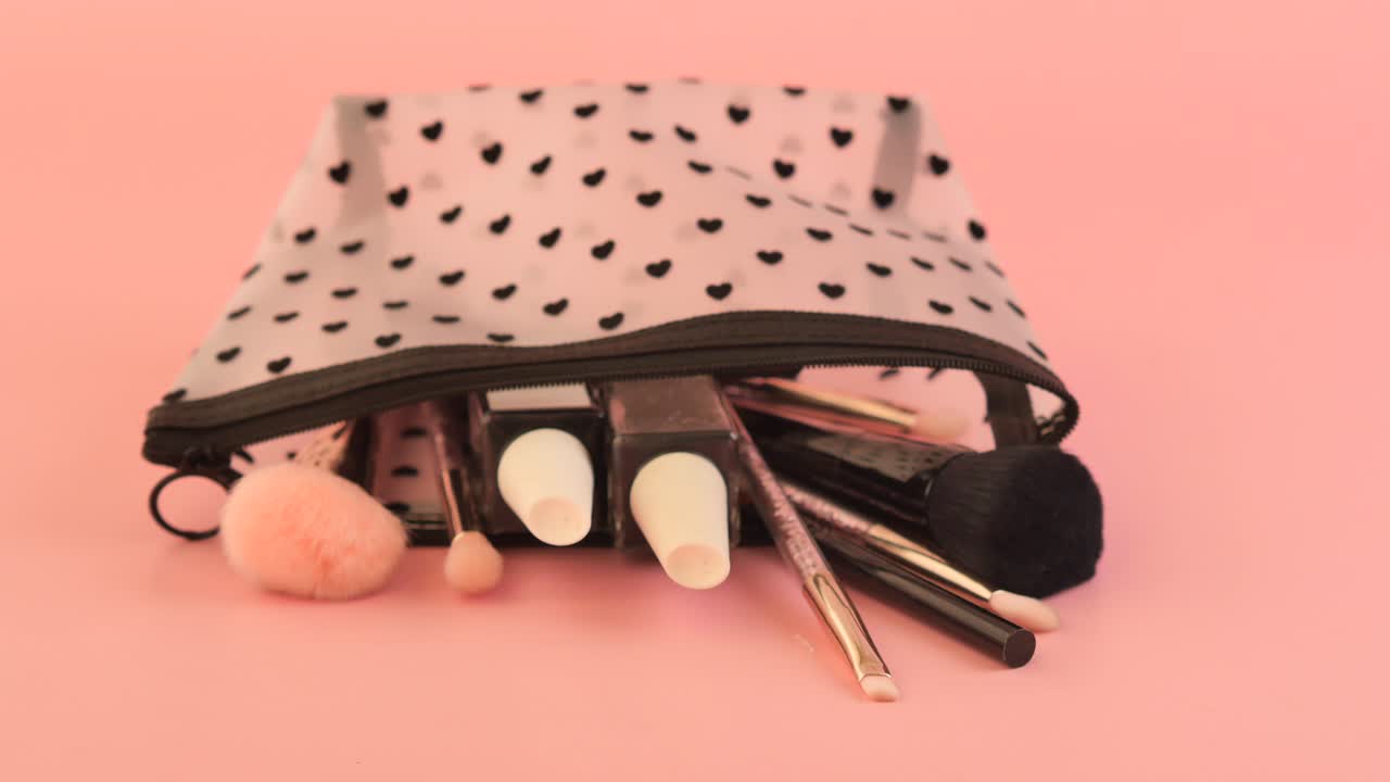Makeup Bag with Brushes and Cosmetics on a Pink Background