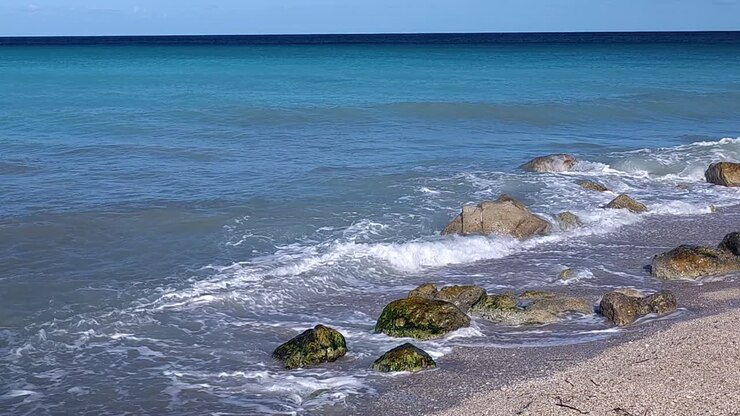 Spiaggia e scogliere bagnate dalle onde del mare in uno splendido panorama con colori blu turchese in una giornata estiva sulla costa mediterranea.
