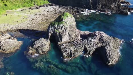 tranquilas aguas cristalinas que rodean las rocas que sobresalen en la costa de la isla del pacífico