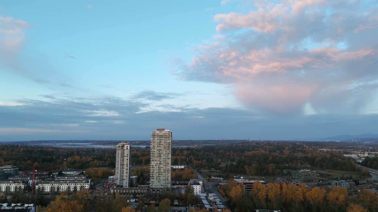 Paisagem urbana suburbana de Carvolth ao anoitecer com altas torres residenciais e o Rio Fraser ao longe. Langley Township, BC, Canadá. Afastamento aéreo descendente.
