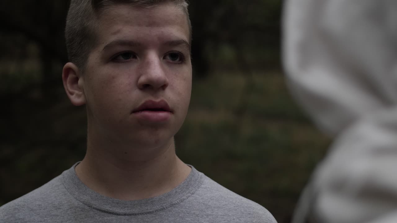 십 대 소년 숲 나무에 서있는 동안 옷을 입은 남자를 찾습니다