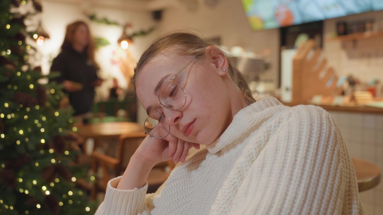 Giovane donna con gli occhiali che dorme serenamente in un caffè