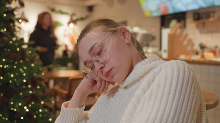 Ung kvinne med briller sover fredelig på en kafé