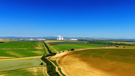 vast landscape with plants and fields. aerial view of green fields and agricultural land with industrial plants under a clear blue sky