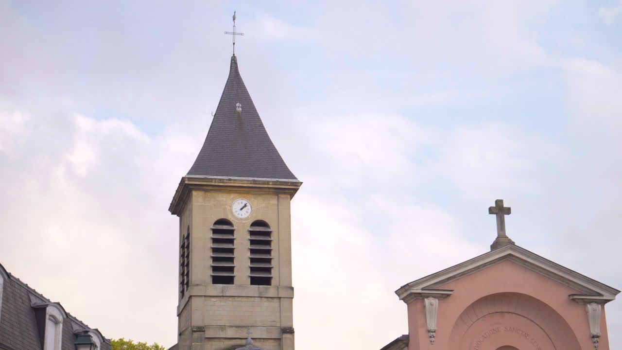Daytime shot of Sainte Geneviève Church steeple in Asnières-sur-Seine, consecrated in 1541.The bell tower stands against the sky, showcasing this small, historic church’s timeless French architecture.