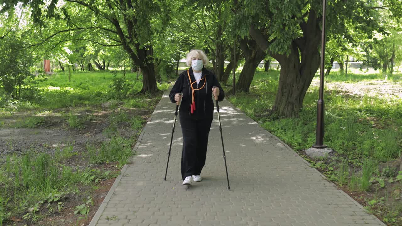 마스크를 착용한 활동적인 고령 여성 훈련 노르이 격리된 공원에서 고 있습니다.