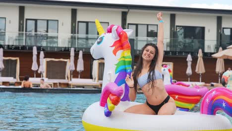 mujer divirtiéndose en la piscina con un unicornio inflable