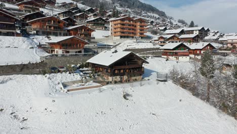 drone flying away from a beautiful wooden chalet in a small swiss touristic town